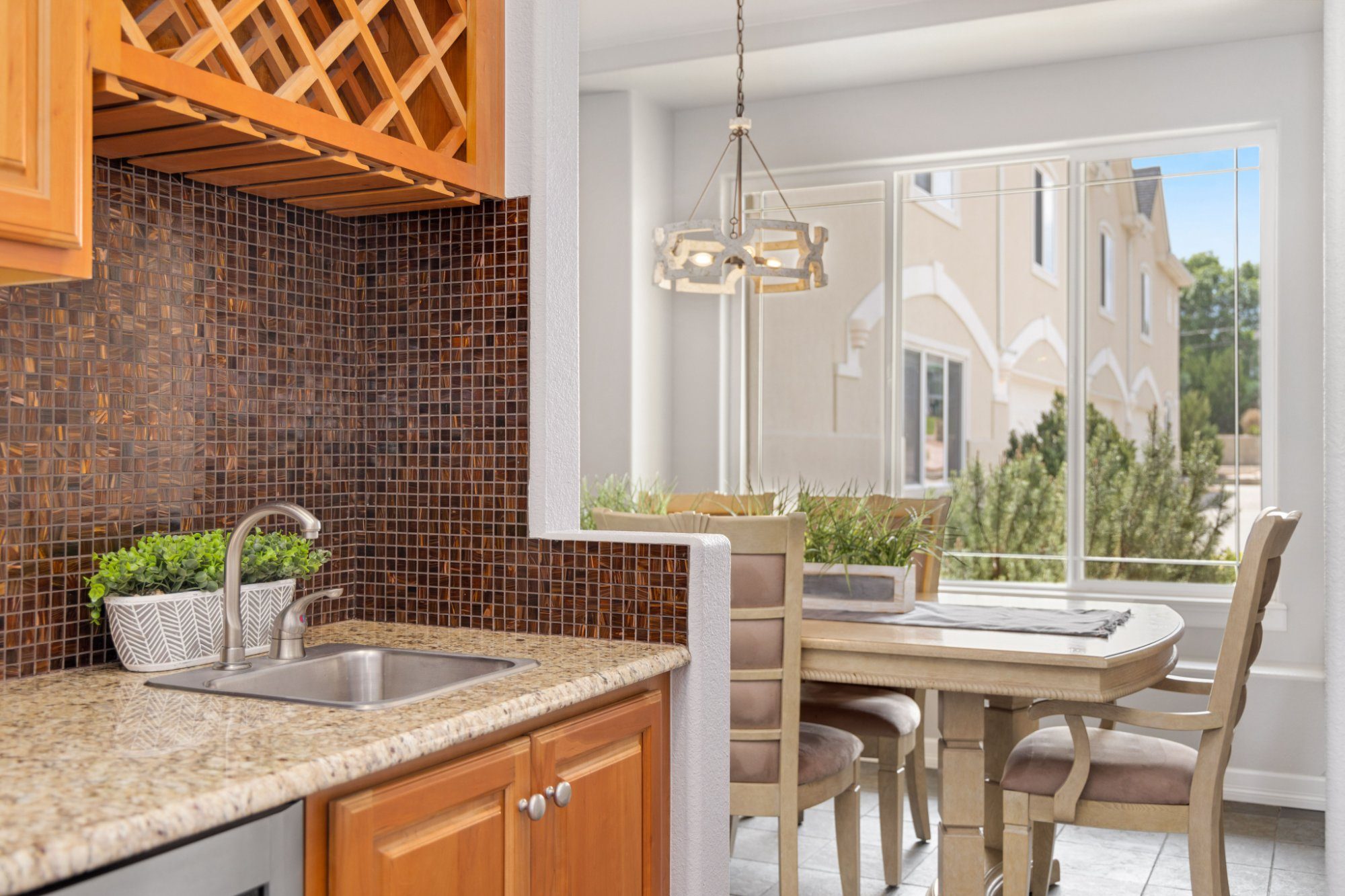 Kitchen wet bar with a wine rack and mosaic tile beside a bright dining nook